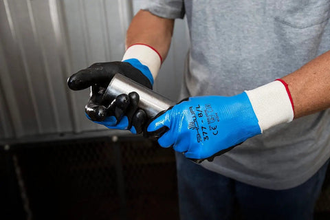 Person wearing fully coated nitrile foam work gloves with nylon liner, gripping metal, 13 gauge large, for wet and oily jobs.
