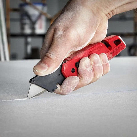 Person using Compatible With Milwaukee Fastback Utility Knife Model 48 22 1502 on a sheet of material, showing red handle and steel blade.