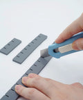 Close-up of hands using a cutter on Flexible Silicone Layout Blocks for stained glass projects.