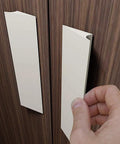 No Sweat Peel And Stick Finger Pull Handles For Cabinets being installed on a wooden surface, white screwless drawer knobs.