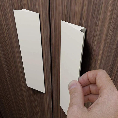 No Sweat Peel And Stick Finger Pull Handles For Cabinets being installed on a wooden surface, white screwless drawer knobs.