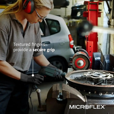 Built Different Black Nitrile Work Gloves With Textured Fingertips And Powder Free Comfort For Kickass Grip During Auto Repair And Industrial Demands Box Of One Hundred worn by a mechanic using a power tool.