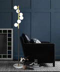 White Glass Shade Marble Base Floor Lamp With Six LED Bulbs Included Modern Mid Century Style next to a black armchair.