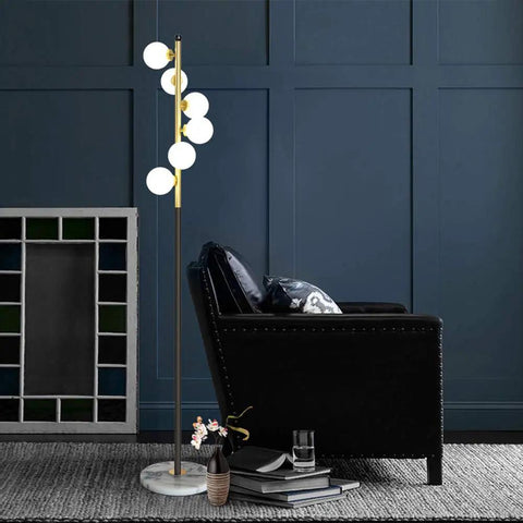 White Glass Shade Marble Base Floor Lamp With Six LED Bulbs Included Modern Mid Century Style next to a black armchair.
