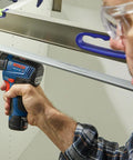 Person using a Bosch cordless drill in a workshop setting