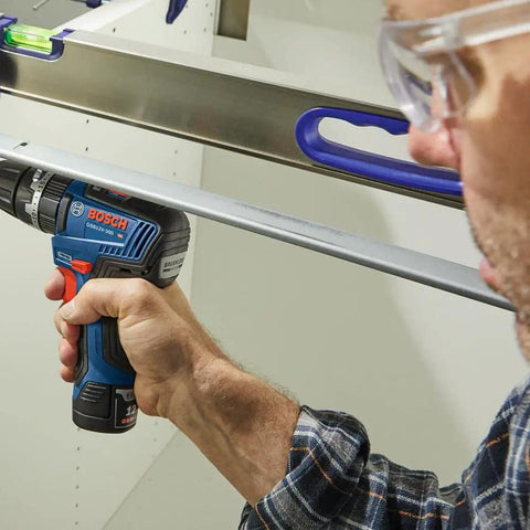Person using a Bosch cordless drill in a workshop setting