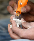 Person using Mini Cordless Rotary Tool Kit With 105 Accessories on a small white object, detailing work visible