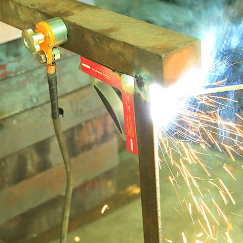 Front view of a 600A magnetic welding ground clamp installed on a steel frame during welding.