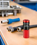 Heavy Duty 5 In 1 Universal Quick Industrial Air Coupler With Dead Simple Setup And Knockout Durability For 1/4 Inch Female Npt Air Compressor Fittings Quick Connect Accessory In Bold Red on workbench with tools.