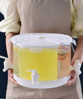 Five Point Five Liter Rotating Beverage Dispenser With Four Separate Compartments And Dripless Spigot in use, dispensing drinks with a sleek white finish.