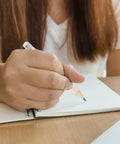 Person writing with 60 Pcs Mini Wooden Pencils With HB Graphite And White Erasers, ideal for school and sketching.