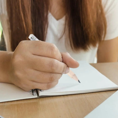 Person writing with 60 Pcs Mini Wooden Pencils With HB Graphite And White Erasers, ideal for school and sketching.