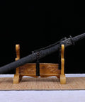 Beefy Damascus Tang Dao Sword With Black Gold Finish on a wooden stand, full tang build with rope wrap handle
