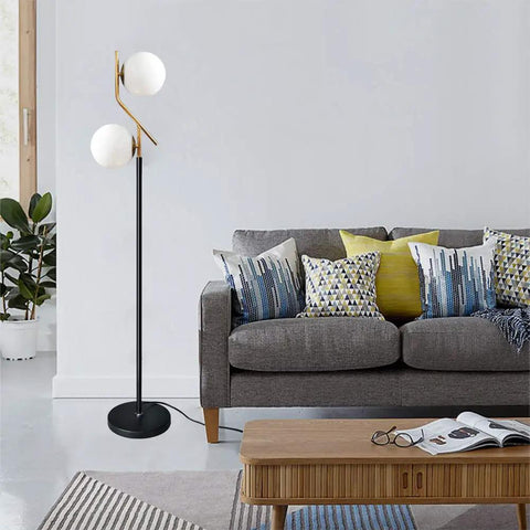 Two Milky White Glass Orbs Brass Finish Floor Lamp With Black Base, Modern Mid Century Style next to gray sofa in living room