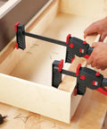 No Sweat One Hand Clamp And Spreader For Tough Woodworking 18 Inch Span shown securing a wooden drawer frame.