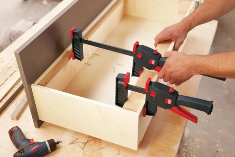 No Sweat One Hand Clamp And Spreader For Tough Woodworking 18 Inch Span shown securing a wooden drawer frame.