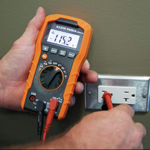 Person using Auto-Ranging Digital Multimeter Pro Grade For DIY And Tech Pros, Reads 600V AC/DC, 10A Current on wall socket.