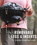Person holding Four In One Portable Propane Grill With Stove Griddle And Wok Attachments, showing removable legs in inverted wok