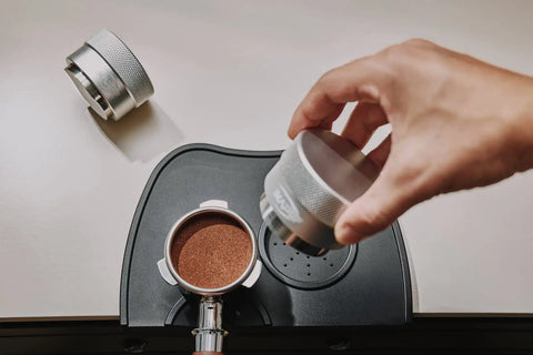 Hand using 53mm Gravity Adaptive Espresso Distributor for 54mm Portafilters, Fits Breville Bottomless Portafilter, 304 Stainless Steel Coffee Tool