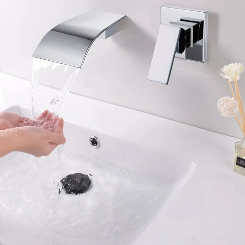 Waterfall Wall Mount Tub Faucet In Brass With Chrome Finish above a white basin, water flowing smoothly, hands catching water