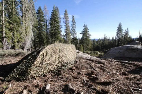 Multicam Camo Netting for Tactical Shelters and SmartFrame Systems set up in a forest terrain, showcasing rugged camouflage.