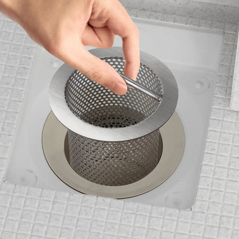 Beefy 4 Inch Commercial Floor Drain Strainer With A 6 Inch High Thick Stainless Steel Basket Finely Polished Finish Rust Resistant Easy Dump Bar Handle For Quick Cleanup Built Tough For Harsh Environments being lifted by hand