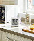 Purple Lavender Farm Wooden Cube LED Digital Alarm Clock on kitchen countertop showing time, date, and temperature.