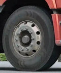 Two Piece Premium Rubber Wheel Bearing Protectors For Cars Trucks And Trailers Slick Hub Dust Guards installed on a truck wheel.