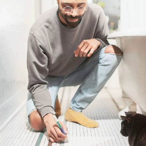 Man using Beige Tile Grout Pen For Waterproof Grout Paint And Sealer Colorant With Narrow 5mm Tip 7mL on bathroom floor.