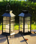 Two Pack Lit Solar Powered Outdoor Hanging Lanterns With Waterproof LED Flickering Flameless Candles, on wooden table