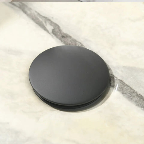 Black pop-up drain on a 16 X 12 Inch Black And White Marble Vessel Sink And Faucet Combo For Modern Bathrooms Durable Porcelain Ceramic Vanity Basin With Sleek Black Faucet And High Temp Glazed Finish For A Dope Modern Look surface
