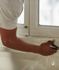 Person cutting plastic for Winter Window Insulation Kit With Roll Shrink Film That Covers Up To 15 Windows Measuring 3 By 5 Feet Tape Included