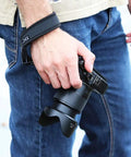 Person using Quick Release Soft Neoprene Camera Hand Wrist Grip Strap For Lightweight DSLRs and Mirrorless Cameras outdoors