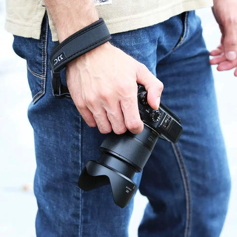 Person using Quick Release Soft Neoprene Camera Hand Wrist Grip Strap For Lightweight DSLRs and Mirrorless Cameras outdoors