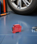 Slick Automatic Aerosol Fire Extinguisher With Smart Sensor Detection on garage floor, compact design fits cars and trucks.