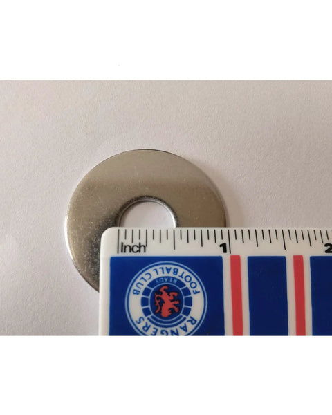 Stainless steel fender washer with a 1/2-inch hole and 1-1/2-inch outer diameter beside an inch ruler.