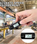 Hand holding Grab And Go Pocket Sized Infrared Thermometer With Contactless Reading Handheld Temperature Pen LCD Display Surface Temp Reader in industrial setting.