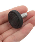 Close-up of a hand holding a small black plastic leveling shim with threaded metal screw. Not related to 20Pcs Furniture Leveling Shims Set.