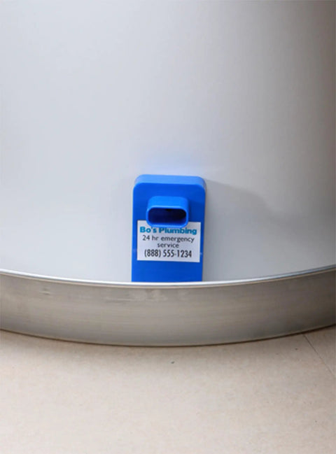 Blue Model Water Leak Alarm For Water Heaters And Pans placed beside a water heater, ready to use with factory-installed battery.