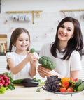 Mother and daughter in kitchen with Premium Stainless Steel Veggie Steamer Basket filled with fruits and vegetables.