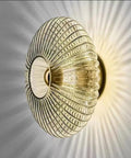 Awsinil Fluted Glass Wall Sconce, Modern Iron Round Decorative Wall Light with ribbed glass shade, emits soft light beams.