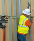 Magnetic Pocket Laser Level With 360 Degree Wall Attachment projects red line on wall for precise alignment by construction worker.