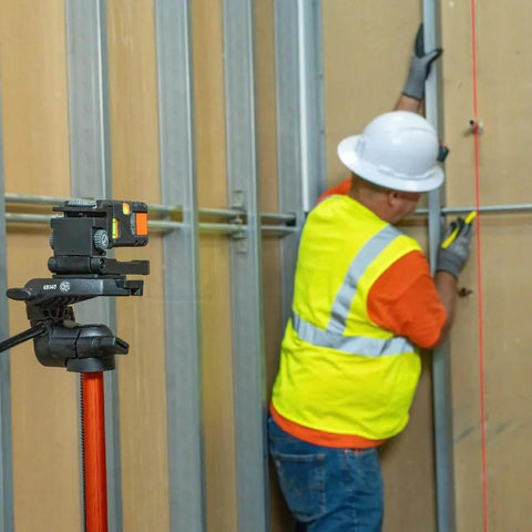 Magnetic Pocket Laser Level With 360 Degree Wall Attachment projects red line on wall for precise alignment by construction worker.