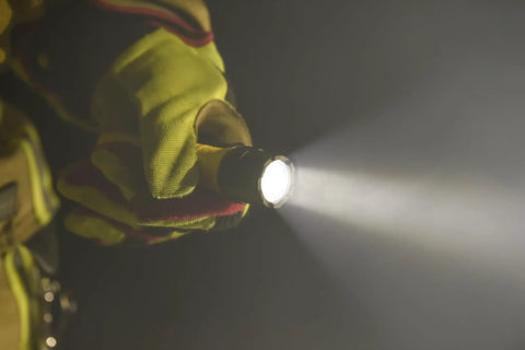 Person holding PolyTac X 600 Lumen Tactical LED Flashlight With Ten-Tap Programmable Modes, beam illuminating darkness