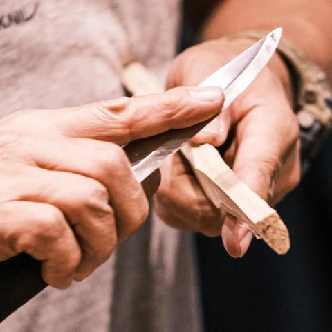 Person using Companion Carbon Steel Fixed Blade Knife With Sheath 4.1 Inch Blade Military Green for whittling wood outdoors.