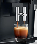 Recertified S8 Automatic Coffee And Espresso Maker In Slick Piano Black Featuring Color Touchscreen Aroma Grinder And Fine Foam Tech brewing espresso into a glass.