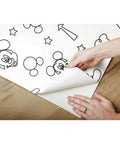 Hands applying Disney Mickey Mouse Icons Silver Peel And Stick Wallpaper Easy To Apply No Mess Removable And Repositionable Self Adhesive Wall Covering For Kids Rooms And Nurseries A Fresh Modern Metallic Silver Decor Upgrade