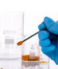 Stainless Steel Micro Spatula With Spoon End 6 Inch Dual End Precision Tool For Lab Sampling And Mixing, Durable Stainless Steel Construction For Precise Measuring And Transferring Tiny Bits In The Lab. gloved hand holding spoon-end micro spatula with powder