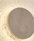 Close-up of yellow travertine round wall sconce modern indoor fixture with textured surface for vintage industrial style.