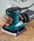 Quarter Sheet Finishing Sander With Ball Bearing Construction Easy Paper Clamp Through The Pad Dust Collection System 1.6 Amp Power in use on wood